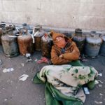 Man sleeps next to a queue of cooking gas cylinders outside a gas filling station amid a scarcity in cooking gas supplies in Sanaa, Yemen