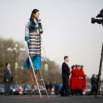 Journalist reports on a ladder outside the Great Hall of the People during the opening session of the National People’s Congress (NPC) in Beijing