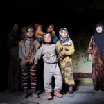 Internally displaced Syrians stand inside their makeshift shelter that is an underground cave in Om al-Seer, southern Idlib countryside, Syria