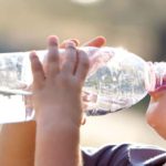 Young boy outside, drinking from a water bottle