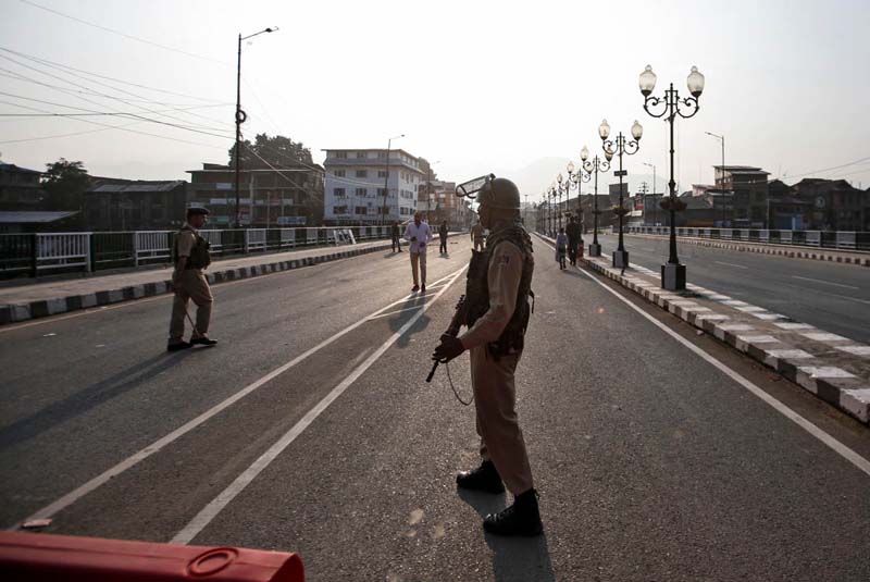 Indian security personnel stand guard on a deserted road during restrictions in Srinagar